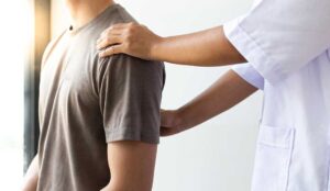 Adult discussing abdominal discomfort with a clinician in a bright examination room.