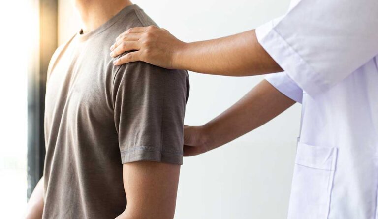Adult discussing abdominal discomfort with a clinician in a bright examination room.