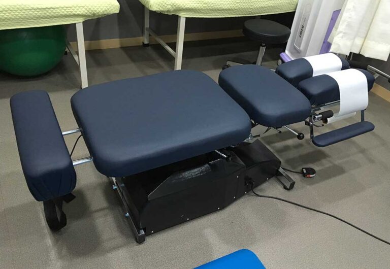 Person lifting a box close to the body with bent knees in a clear, well-lit room.