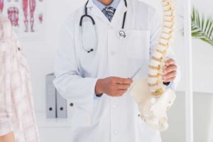 A chiropractor guides an adult through a gentle mobility exercise beside a treatment table.